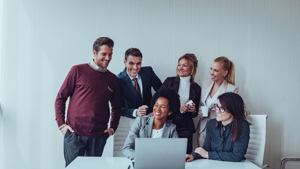 Diverse group of professionals discussing health policy around a laptop, representing collaboration on the public option for health insurance.
