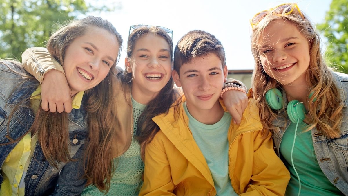 Group of smiling teenagers outdoors, symbolizing community and support, representing the idea of medical cost sharing.