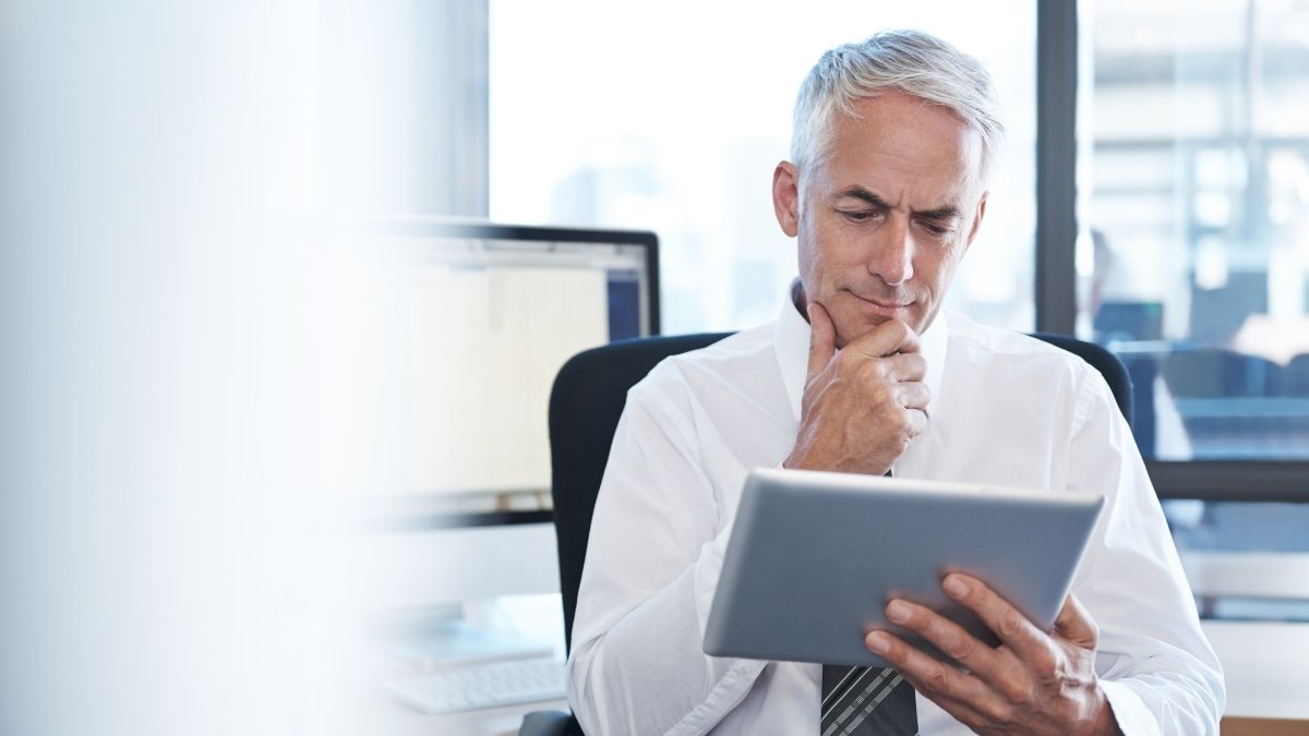 Businessman reviewing information on tablet, reflecting on common health insurance myths