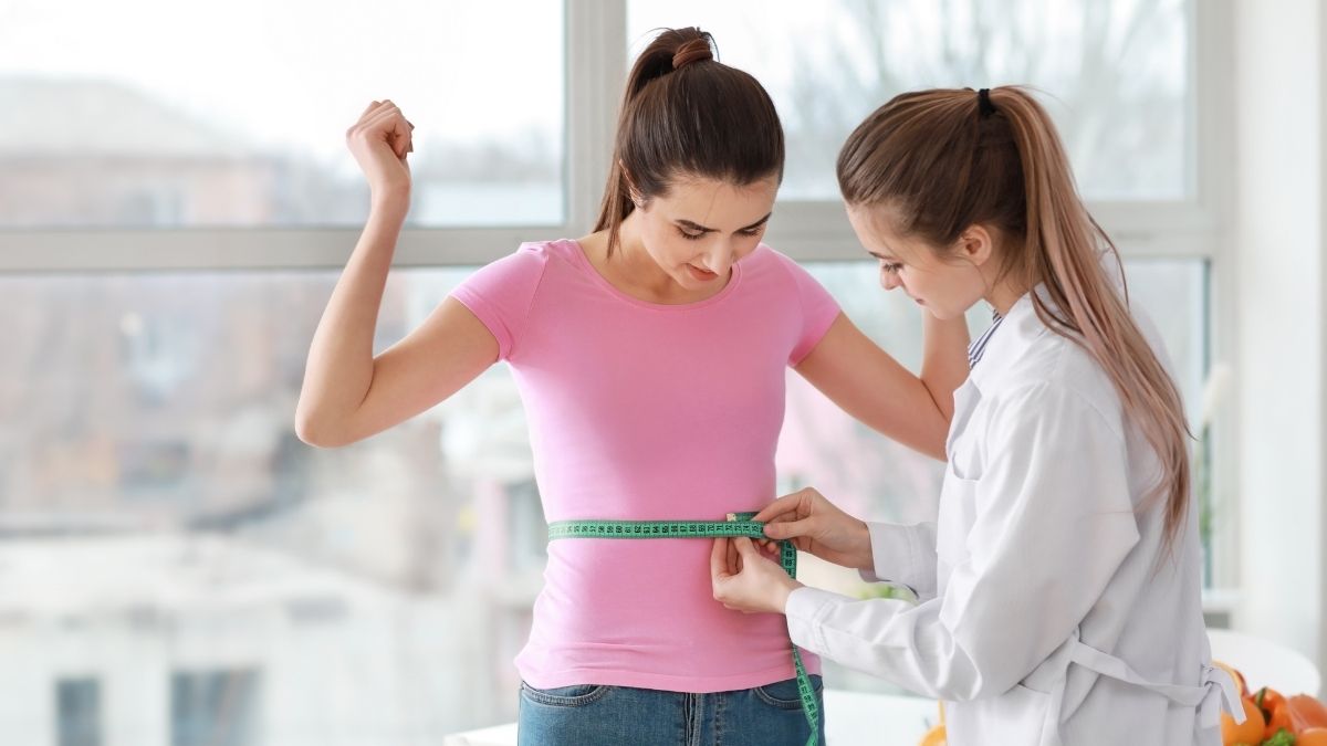 Healthcare professional measuring a woman's waist as part of a medical weight loss program