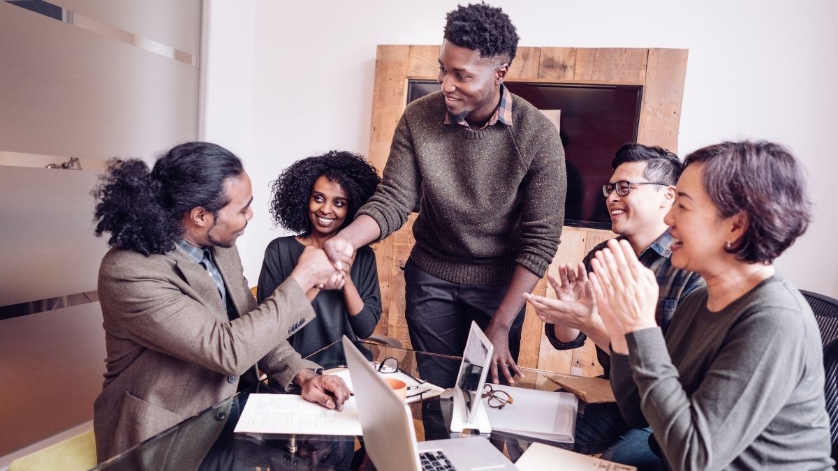 Diverse team celebrating in a meeting, highlighting effective employee benefit communications to boost engagement and retention.
