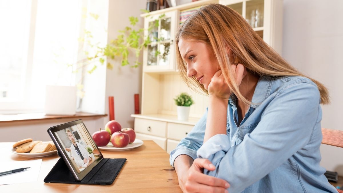 Woman having a virtual consultation with a doctor on a tablet at home, highlighting the convenience and accessibility of telehealth benefits.
