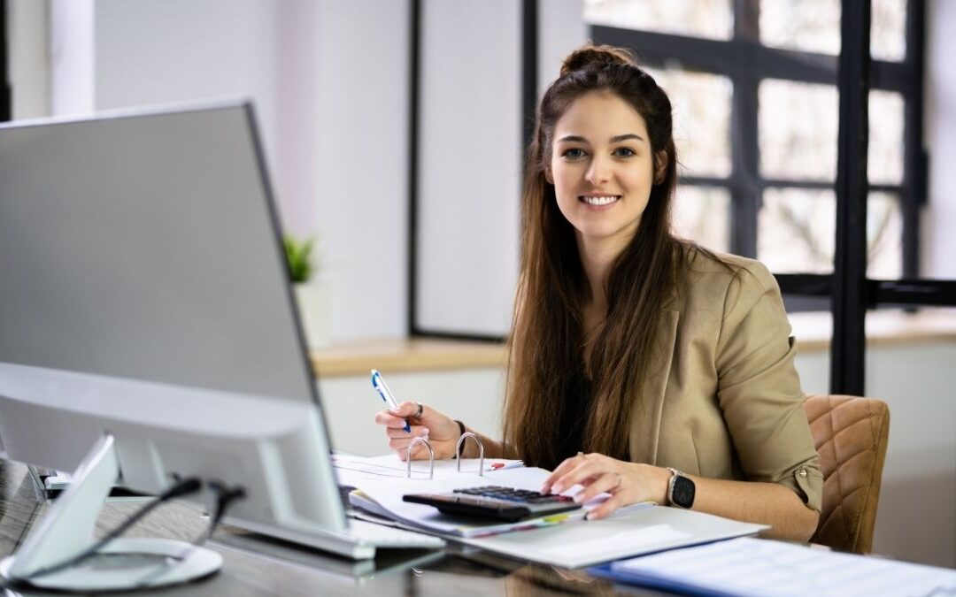 Financial advisor researching the best HSA options while working at her desk with a computer and calculator.