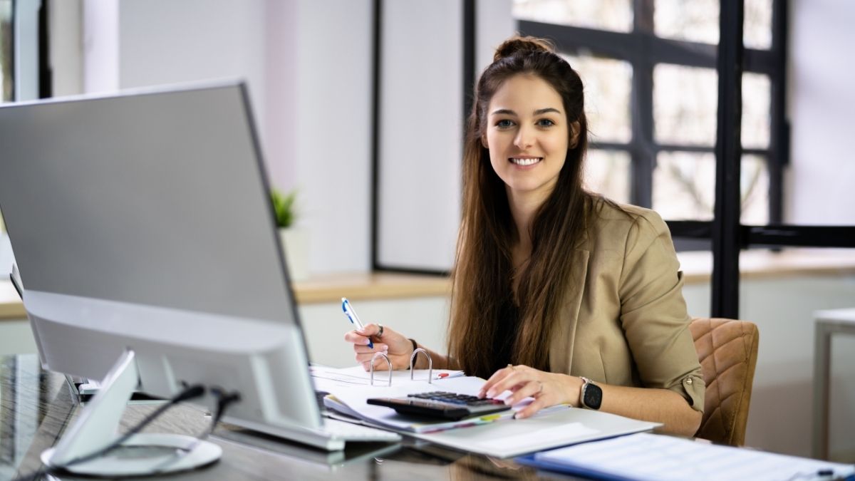 Financial advisor researching the best HSA options while working at her desk with a computer and calculator.