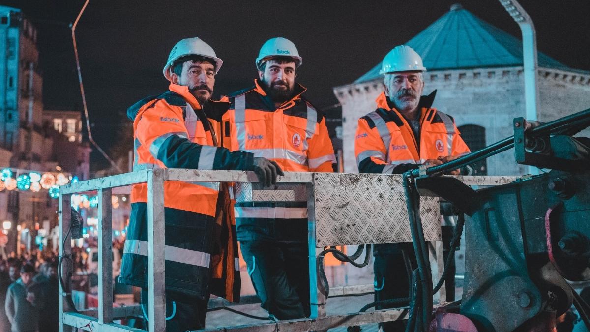 Utility workers in safety gear on a lift at night, symbolizing the importance of health insurance for remote workers in demanding environments.