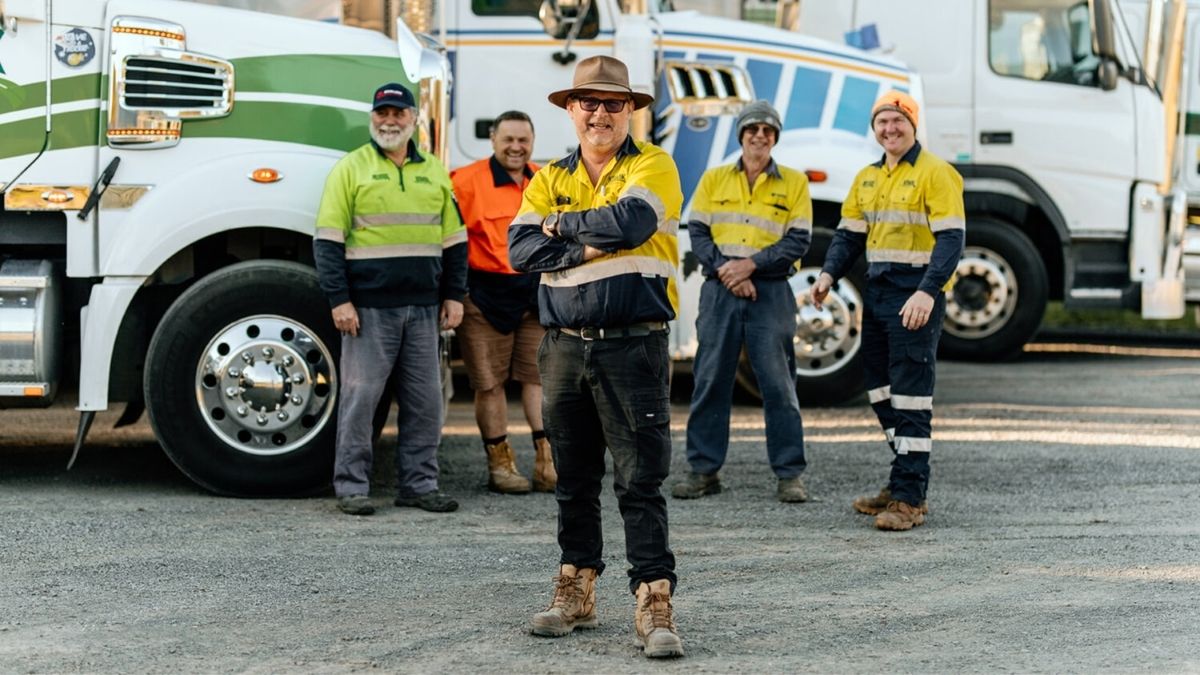 Group of truck drivers standing in front of their trucks, symbolizing the importance of health insurance for truck drivers.