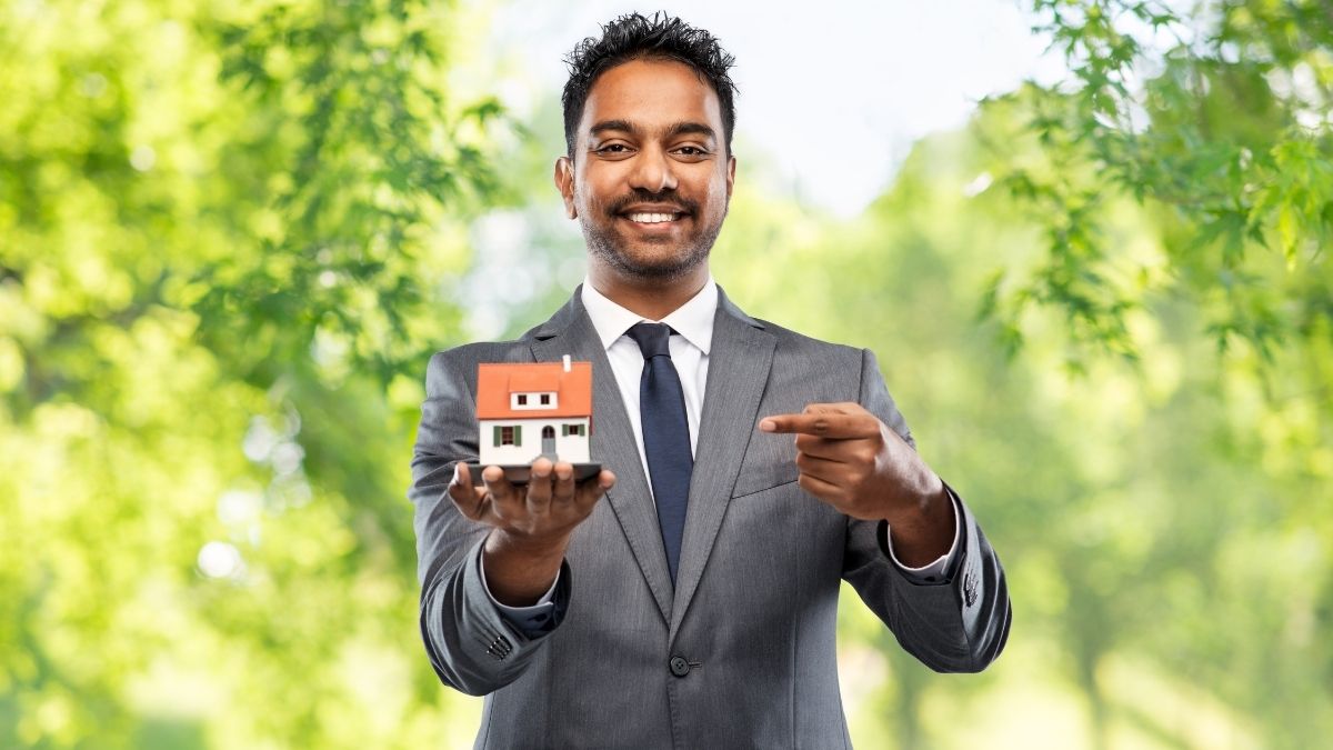 Health insurance for realtors real estate agent holding house model outdoors.