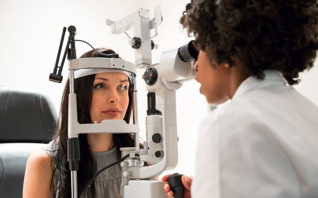 Optometrist performing an eye exam on a patient using specialized equipment, representing eye exam cost without insurance.