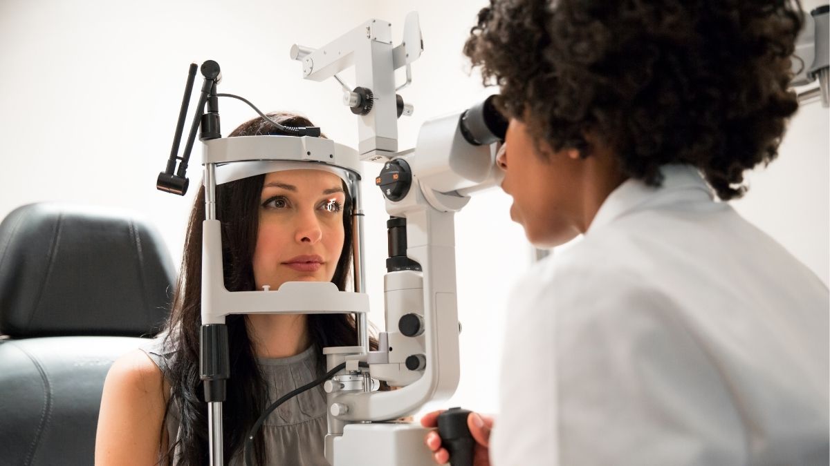 Optometrist performing an eye exam on a patient using specialized equipment, representing eye exam cost without insurance.