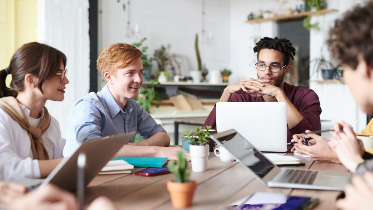 Small business team discussing options on how to get health insurance for employees during a meeting with laptops and notes.