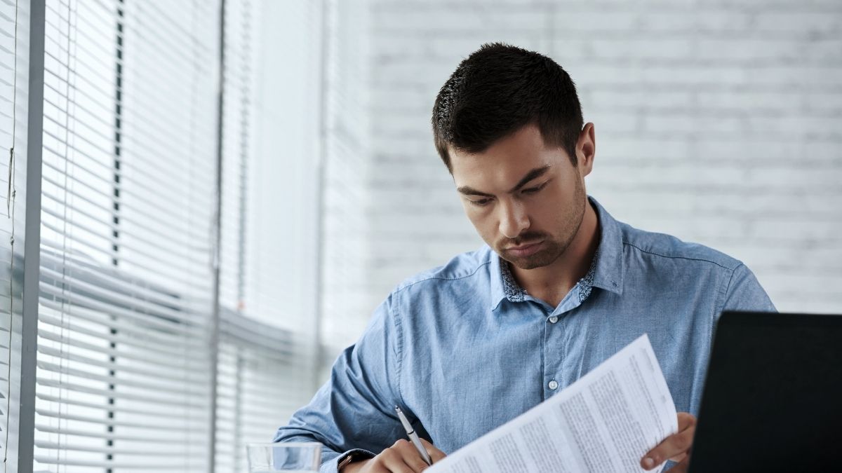 Man reviews health insurance documents at his desk while researching alternatives to COBRA coverage.
