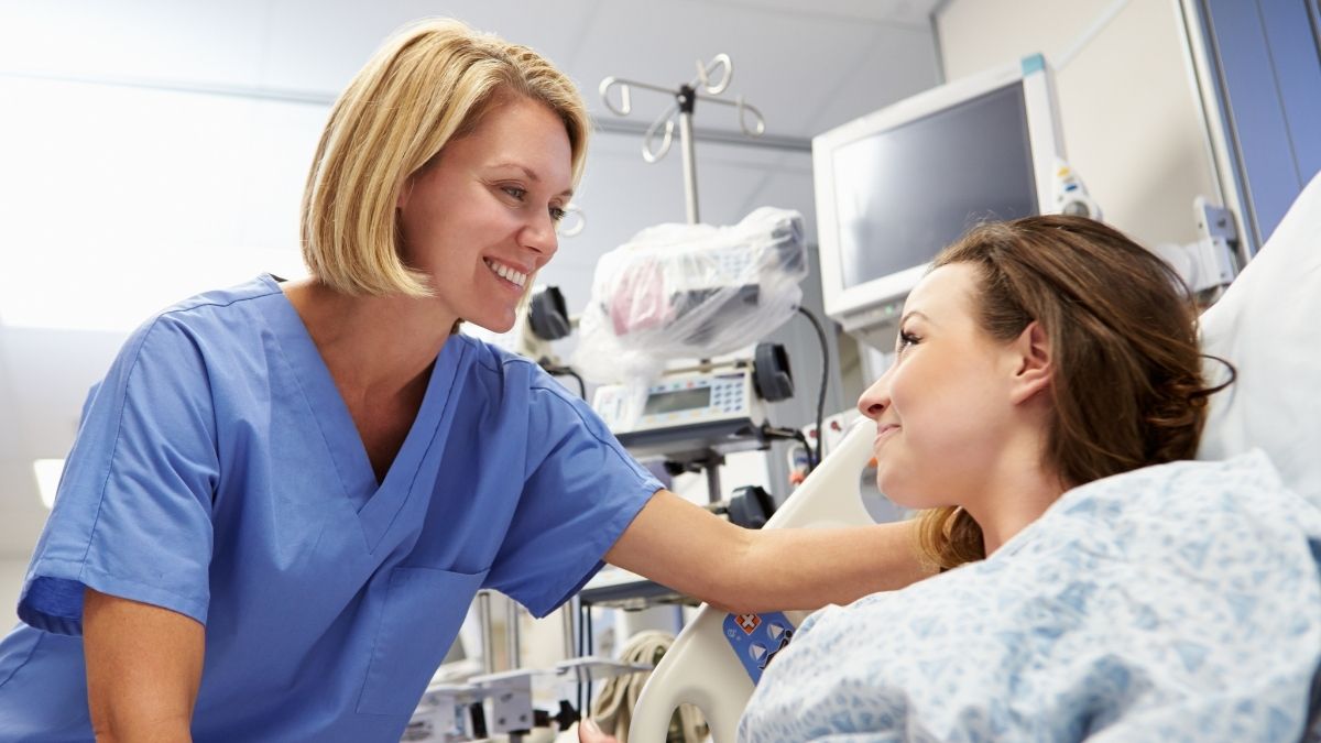 Nurse comforting a patient in a hospital bed, illustrating how much is ER visit with insurance for medical care.